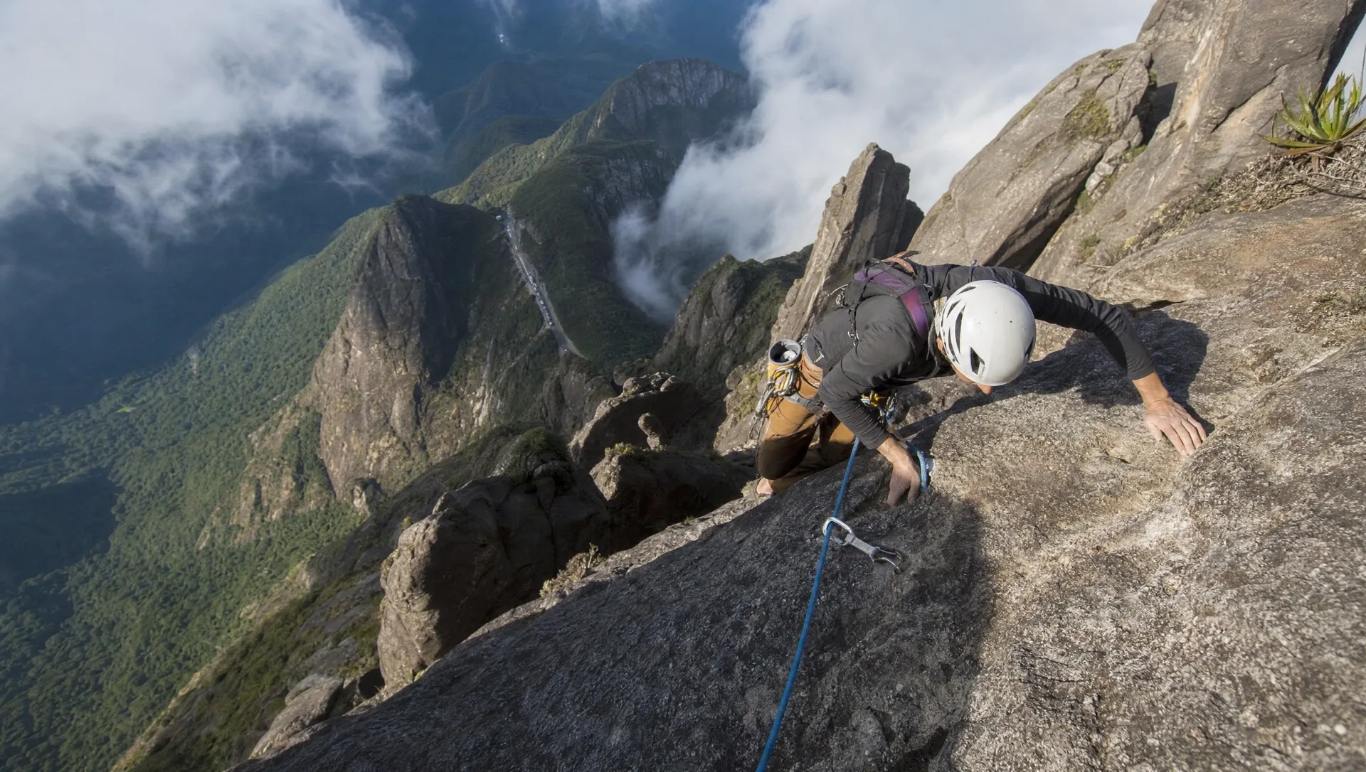 Escalador com capacete em parede exposta de granito do Dedo de Deus
